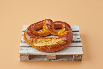 Wooden pallets with pretzel on orange pastel background