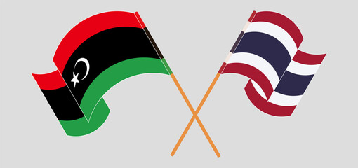 Crossed and waving flags of Libya and Thailand