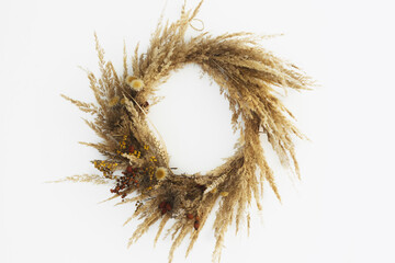 Stylish autumn rustic wreath isolated on white. Creative boho wreath with dried pampas grass, tansy wildflowers, wheat, dog-rose berries on white wall. Space for text. Hello Fall. Happy Thanksgiving