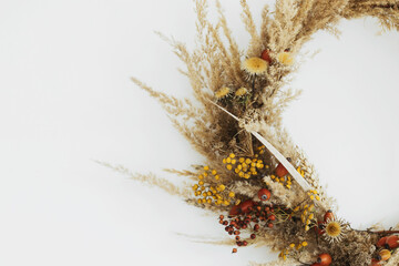 Creative boho wreath with dried pampas grass, wildflowers, wheat,  berries on white wall. Stylish...