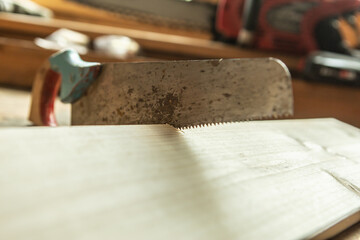 Close-up of a hand saw on a wooden board. Soft focus with text space