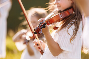 Selective focus at the violin of a young little girl playing outdoor during the summer festival.