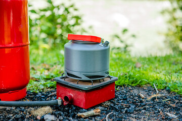 Tourist gas kettle in nature. Camping with a gas kettle. kettle boiling on a camping stove to make...