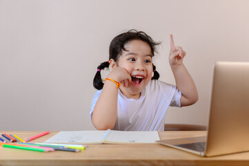 Smiling little Asian girl have video call distant class with teacher using laptop, social distance during quarantine isolation during the Coronavirus (COVID-19) health care