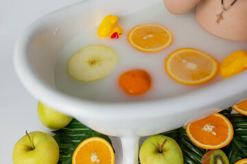 a small child in a bath with milk and oranges
