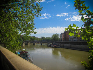 Buildings by a bridge over the Tiber river in Roma, Italy under a sunny sky