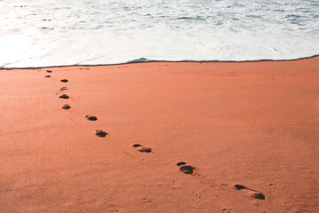Empreintes d'Homme dans le sable avec la mer au loin