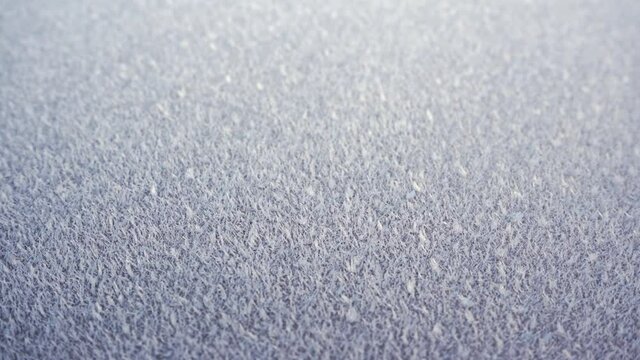 Glossy surface covered in frost frozen ice crystals, close up 4K slow motion