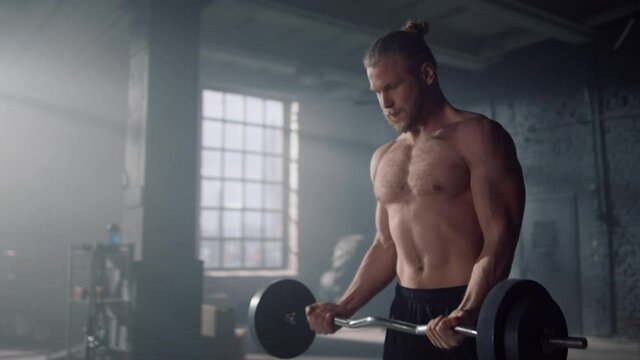 Man doing exercises on biceps muscles in gym. Man screaming during training 