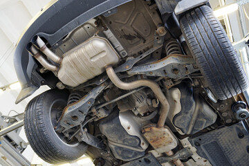 A modern powerful car in a car service on a lift. Bottom view. Details of the suspension and exhaust system are visible.