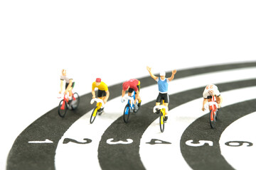 Miniature people toy figure photography. Bike cycling track. A biker cycling above dartboard, isolated on white background.