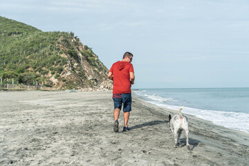 Older Man having fun with his dog on the beach in the morning