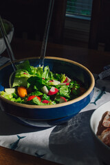 lettuce salad with tomato, radish in blue bowl 