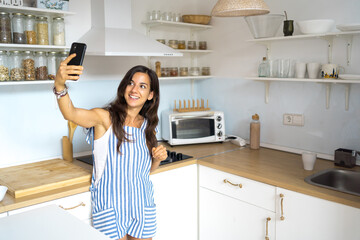 carefree young female at home sending message on electronic device in kitchen