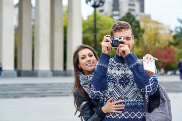 Happy love couple of tourists taking photo on excursion or city tour. Travel together with a map and retro camera
