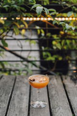 autumn fall cocktail in coupe glass with star anise outdoors with leaves and string lights 