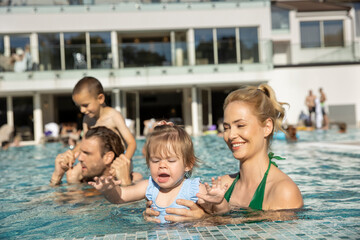 Happy family, parents playing with the kids, mother and daughter  in the swimming pool