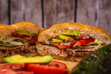mexican pork leg cake SERVED WITH BREAD, TOMATO, ONION, CHILI, AVOCADO ON A TABLE AND WOODEN BACKGROUND