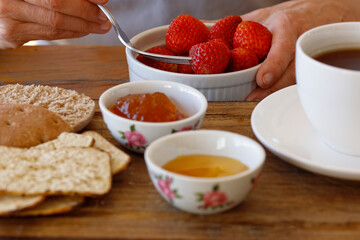 Eating strawberries for breakfast, woman's hands holding a bowl with fruit, healthy eating