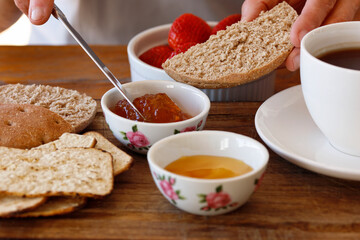 Wholemeal bread with jam for breakfast, woman's hands prepating food