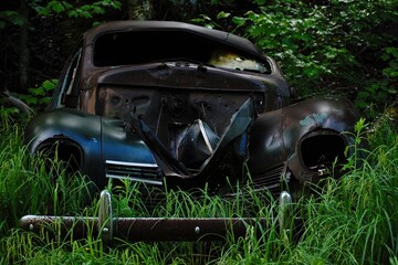 Abandoned vintage green car wreck hidden in a quebec forest.