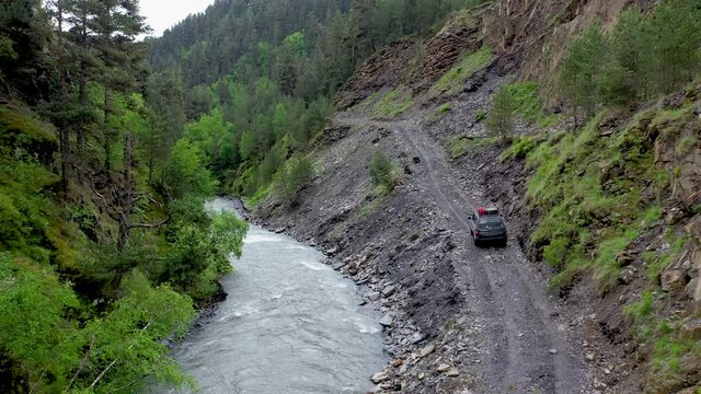 Drone shot of vehicle driving on the Abano Pass, the dangerous road to Tusheti Georgia along side the Alazani River