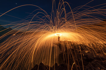 Amazing Fire dancing steel wool coast the sea on bamboo bridge in the twilight, soft and select focus