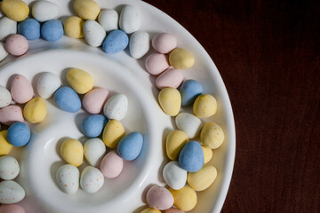 Pastel Chocolate Covered Egg Candy in a White Spiral Bowl on Dark Table
