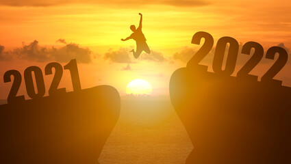 Concept Happy new year 2022 Silhouette image of happy man jump from 2021 up to 2022 on beautiful sky sunrise.