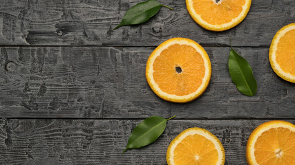 Orange slices with leaves on a wooden background. Space for the text. Flat lay.