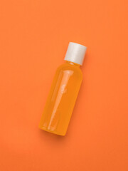 Orange juice in a plastic bottle on an orange background. Minimalism.