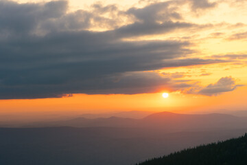 The sun is setting in a mountain valley in summer. panorama of the mountain range at sunset. View from the top.