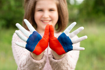Child girl show hands painted in Russia flag colors walking outdoor, focus on hands. Day of Russian flag. Patriots patriotism citizens nationality. June 12. August 22 holiday. November 4