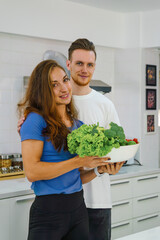 caucasian couple preparing salad for dinner together in kitchen