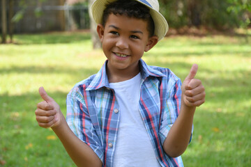 Adorable smiling boy wearing fedora hat with his thumbs up. 