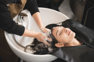Fototapeta premium hairdresser washing client's hair at salon. happy young women customer relax and comfortable while washing hair, luxury hair spa by professional hairstylist