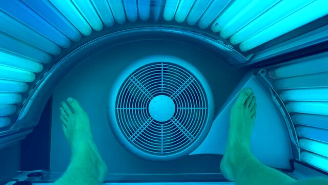 Close up shot of male person taking sunbath in solarium with rotating ventilation. Relaxing in Tanning bed with dangerous light rays
