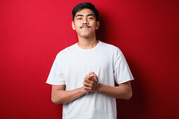 Young handsome man wearing casual shirt with hands together and crossed fingers smiling relaxed and cheerful