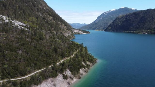 Mountain trail next to the lake Achen. Drone orbiting around an amazing footpath in Alps.