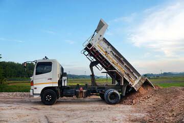 The dump truck is pouring soil out of the pickup truck, on construction site.  © Montree