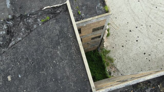 Drone view of a rotting and crumbling roof during a rainstorm.