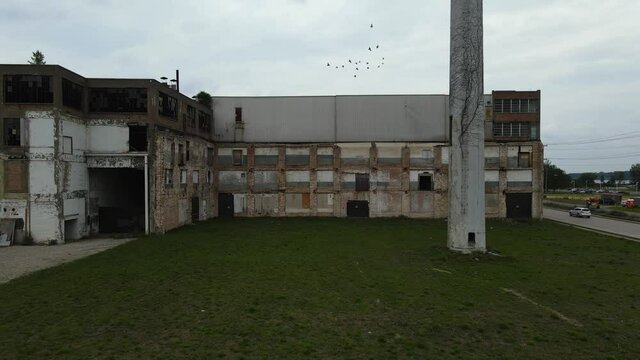 Abandoned factory - panning left as a flock of birds fly through the frame.