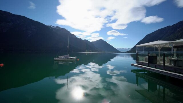 Boat, yacht on Achen lake, early in the morning, water like mirror, beautiful reflection of mountains on the water.