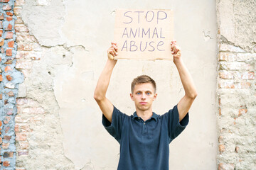 Young man holding the inscription stop animal abuse in his hands. Caucasian guy in protection of...