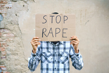Young man holding cardboard with the inscription stop rape. Guy of Caucasian appearance against...