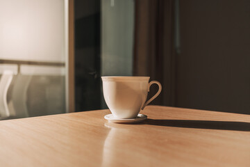 Hot cup of drink on the table in sun light of calm and warm morning.