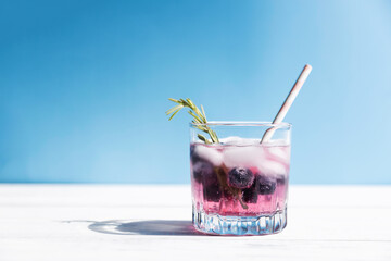 Chilled water, soda, cocktail with fresh blueberries and ice, garnished with a sprig of rosemary. Seasonal, summer drinks. Copy space