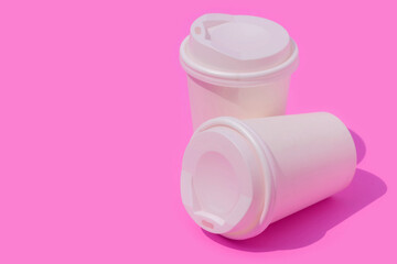 White paper coffee cup with a shadow on a pink background