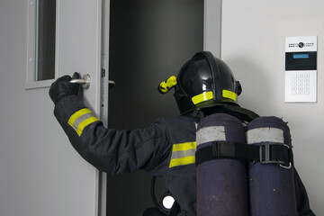 a firefighter in protective clothing and a hard hat, with fire extinguishing equipment, enters the...