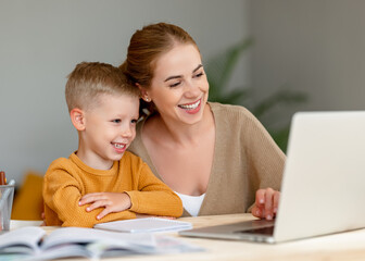 Fototapeta premium Happy mother supporting son during online studies
